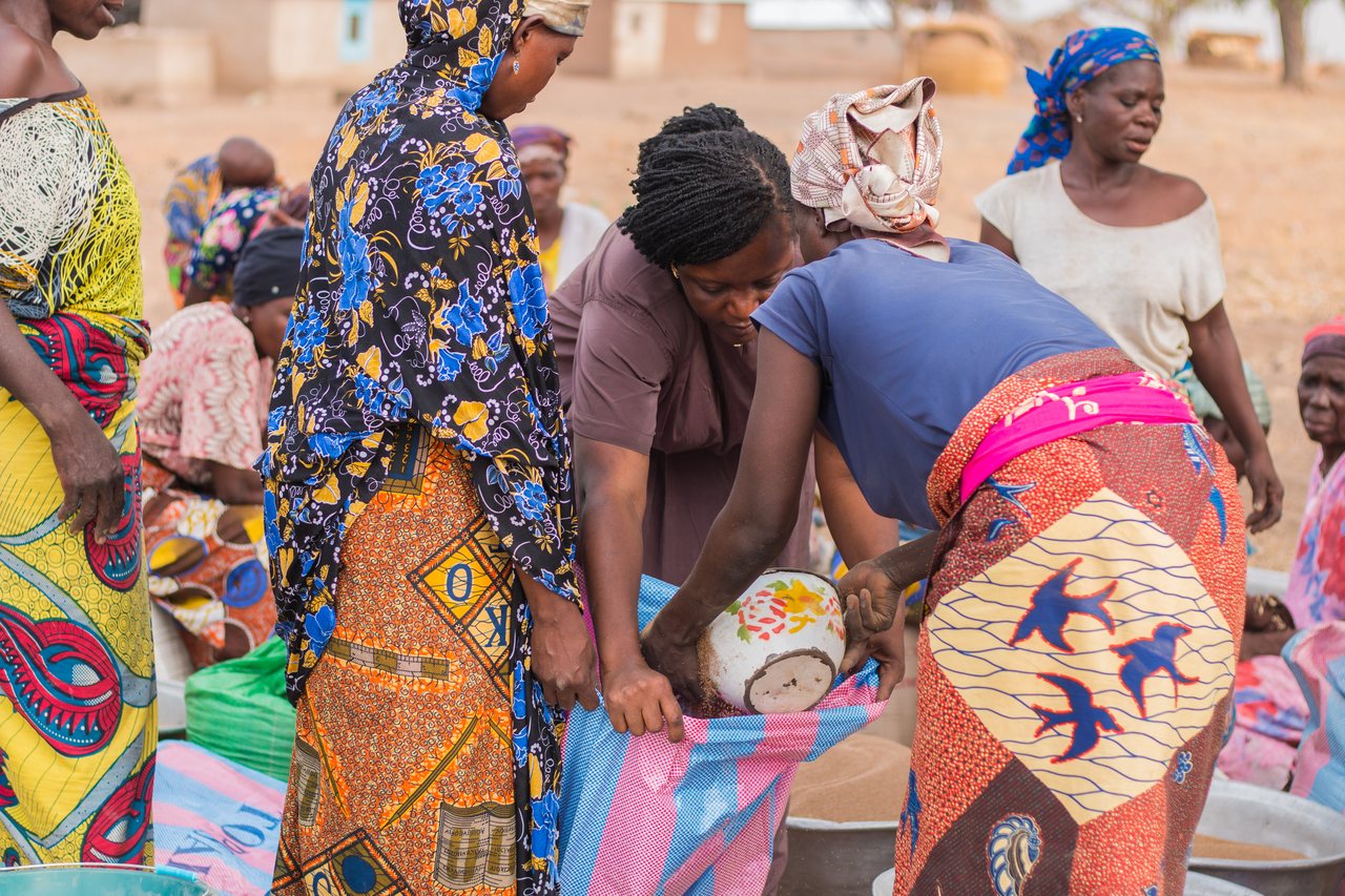 A group of women together, sorting colorful woven cloths by hand.