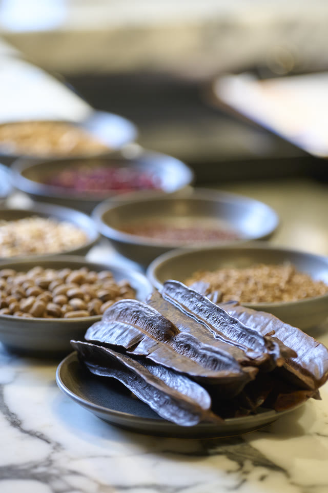 Bowls of grain and spice beside foil-wrapped parcels, on a marble counter.