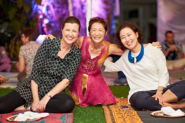 Three women posing together and smiling at an evening event.