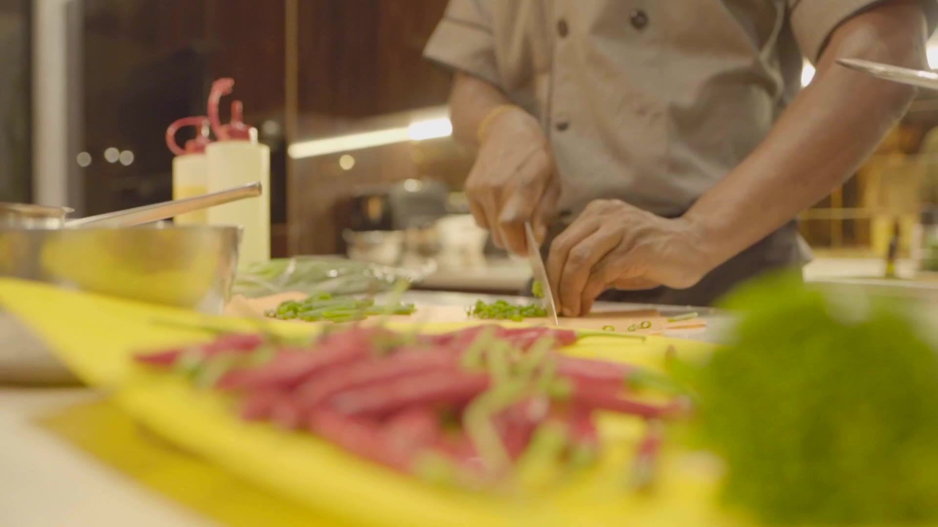 Chef Binta serving guests seated on patterned mats in a warmly lit room