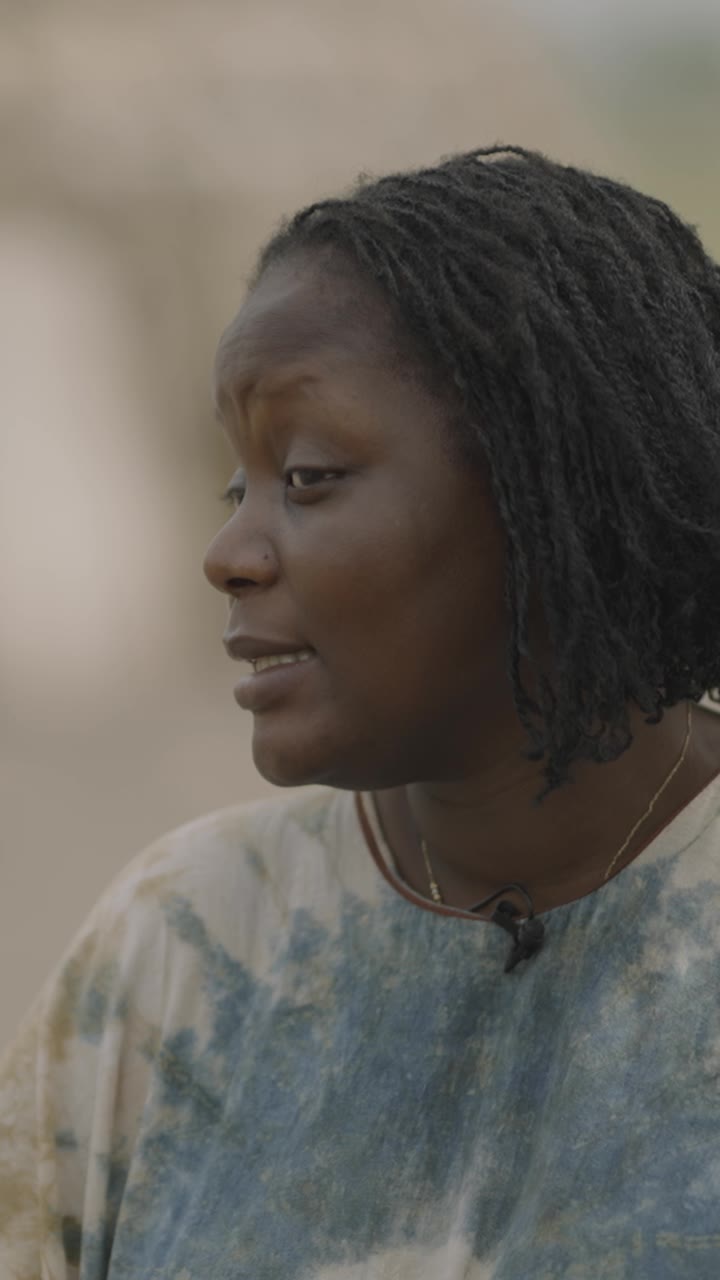 Chef Binta speaking to camera, in a tie-dye top with a small clip microphone